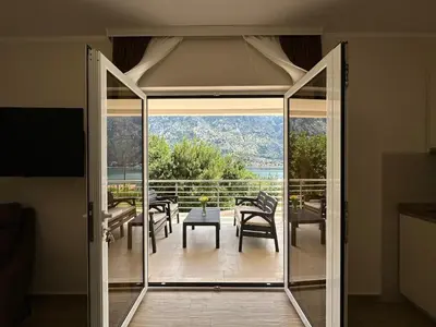 a glass door leading to a patio with a table and chairs at Sea view apartment with heated pool in Kotor