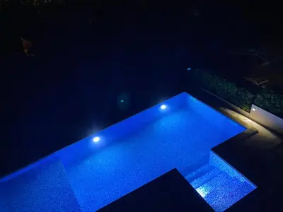 a swimming pool with blue lights in the dark at Sea view apartment with heated pool in Kotor