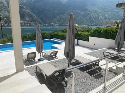 a swimming pool with umbrellas and chairs next to a pool at Sea view apartment with heated pool in Kotor
