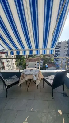 a table and chairs on a balcony with a curtain at Blue wave apartman in Becici