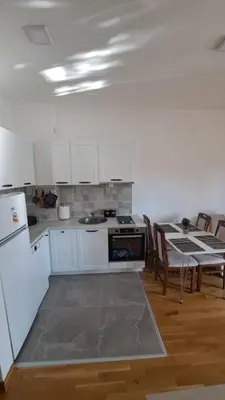 a kitchen with white cabinets and a table with chairs at Blue wave apartman in Becici