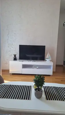 a living room with a tv on a white entertainment center at Blue wave apartman in Becici