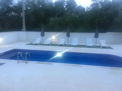 a swimming pool with chairs and umbrellas at Apartment Alma in Kravlja