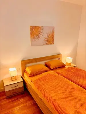 a bedroom with an orange bed with two lamps at Monte Rama Suite Rafailovici in Budva