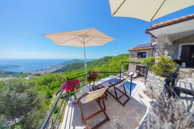 a balcony with a table and chairs and an umbrella at Villa Rustique in Budva
