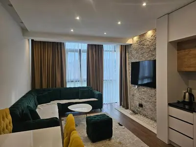 a living room with a green couch and a television at Moon Apartment in Ulcinj