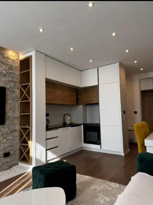 a kitchen with white cabinets and a living room at Moon Apartment in Ulcinj