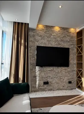 a living room with a brick wall with a flat screen tv at Moon Apartment in Ulcinj