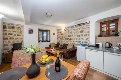 a kitchen and a living room with a table and chairs at Vila Lancana in Kotor