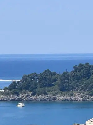 a boat in the water next to an island at Apartments EVG in Rafailovici