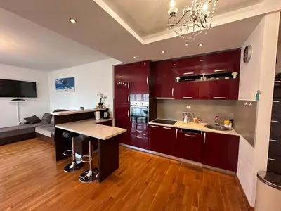 a kitchen with red cabinets and a table in it at Apartments EVG in Rafailovici