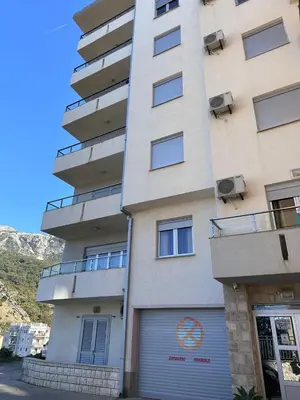 a tall building with a garage in front of it at Apartments EVG in Rafailovici