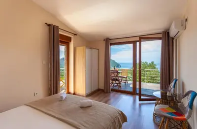 a bedroom with a bed and a balcony with a view at Eco Villa Buljarica in Buljarica