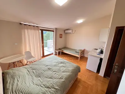a bedroom with a bed and a desk and a window at Eco Villa Buljarica in Buljarica