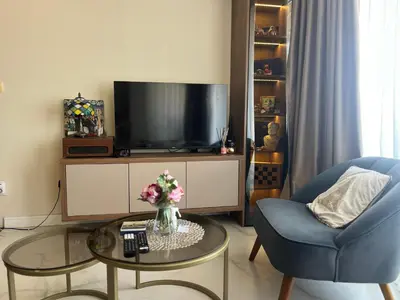 a living room with a tv and a blue chair and a table at sinbia apartment in Budva