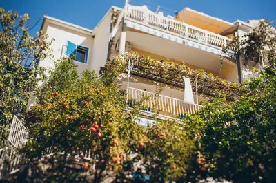 a building with a balcony with plants on it at Apartmani Famelja Jovanovic in Sveti Stefan