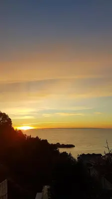 a sunset over a body of water with the sun setting at Apartmani Famelja Jovanovic in Sveti Stefan