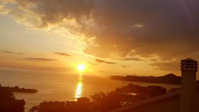 a sunset over the ocean with the sun setting at Apartmani Famelja Jovanovic in Sveti Stefan