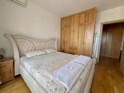 a bedroom with a large white bed with wooden cabinets at Plaza Apartment in Budva