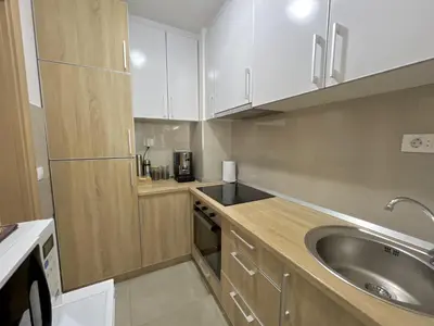 a kitchen with white cabinets and a sink at Plaza Apartment in Budva