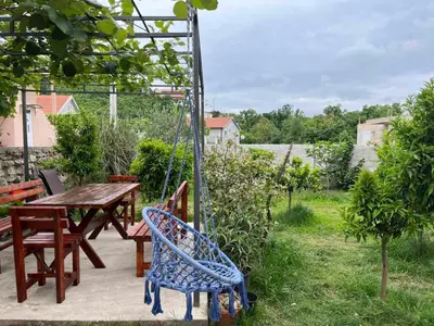 a patio with a table and chairs and a swing at Lutovac Apartmani in Kotor