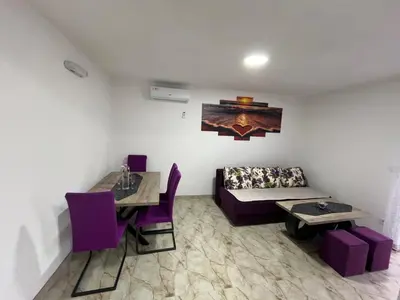 a room with a couch and a table and purple chairs at Lutovac Apartmani in Kotor
