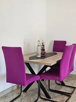 a wooden table with purple chairs in a room at Lutovac Apartmani in Kotor