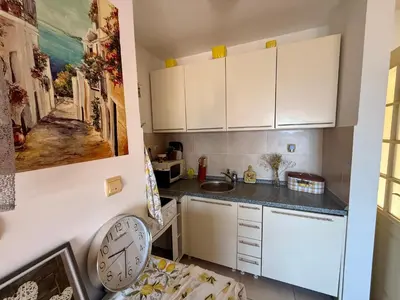 a kitchen with white cabinets and a clock on the wall at La Marea in Petrovac na Moru