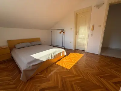 a bedroom with a bed and a wooden floor at La Marea in Petrovac na Moru