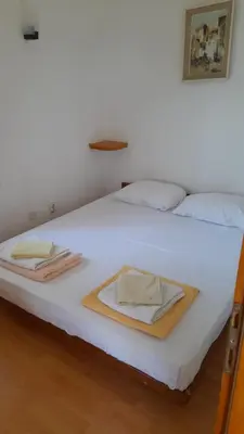 a white bed with two towels on top of it at Apartments Perazica Do in Sveti Stefan
