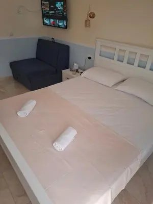 a bedroom with a large white bed and a couch at Apartments Sophia in Ulcinj