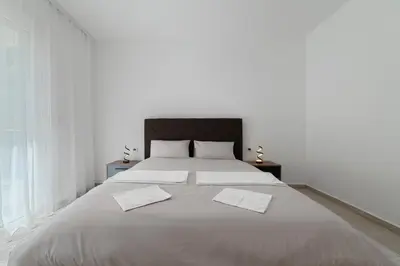 a white bedroom with a large bed with two white pillows at MM Apartments Brown in Budva