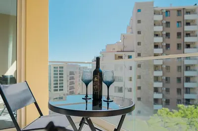 a table with a bottle of wine and glasses on a balcony at MM Apartments Brown in Budva