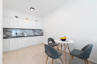 a kitchen with white cabinets and a table and chairs at MM Apartments Brown in Budva