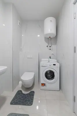 a white bathroom with a toilet and a washing machine at MM Apartments Brown in Budva