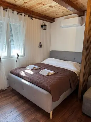 a bed in a bedroom with a wooden ceiling at Airport apartments Jelena in Podgorica