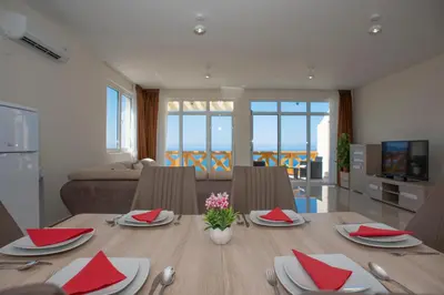 a living room with a dining room table with red napkins at Berg Apartments in Bar