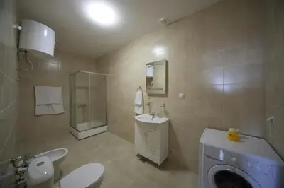 a bathroom with a toilet sink and a washing machine at Berg Apartments in Bar