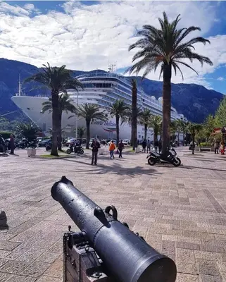 a cannon in front of a cruise ship with palm trees at Apartman Jelena in Kotor