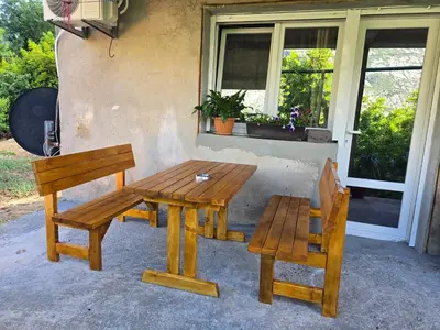 a wooden picnic table and two chairs next to a window at Apartman Jelena in Kotor