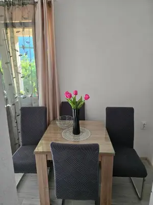 a dining room table with a vase of flowers on it at Apartman Jelena in Kotor