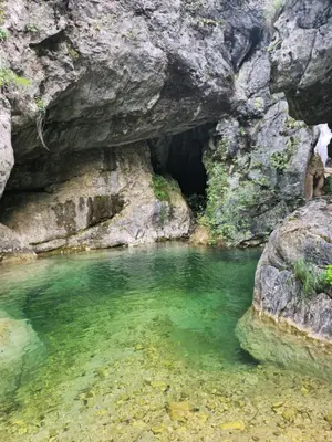 a cave in the rocks with a pool of water at LU House in Virpazar