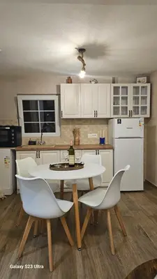 a kitchen with a table and chairs with a bottle of wine at LU House in Virpazar