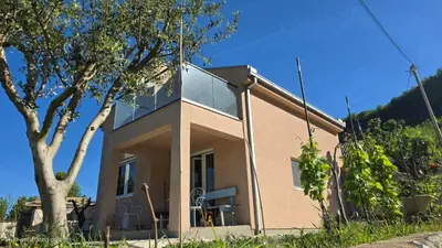 a house with a large window on the side of it at LU House in Virpazar