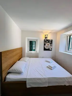 a bedroom with a large white bed with two windows at 2 Charming Apartment in Kotor Old Town in Kotor