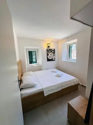 a bedroom with a large bed with two windows at 2 Charming Apartment in Kotor Old Town in Kotor