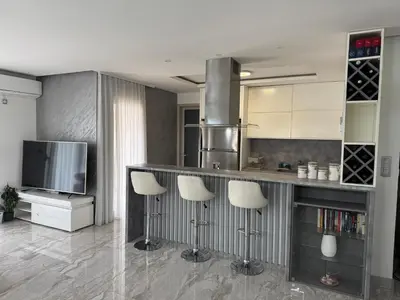 a kitchen with a bar with stools and a tv at Lux Apartment 14 in Kravlja