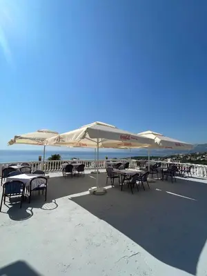 a patio with tables and umbrellas on the beach at Vidikovac in Utjeha