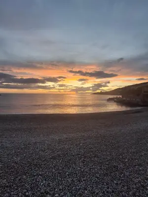 a sunset on a rocky beach with the ocean at Vidikovac in Utjeha