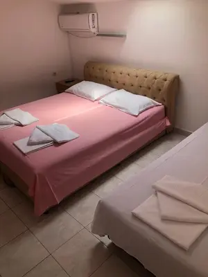 a bedroom with a large bed with pink sheets at Apartmani Centar in Petrovac na Moru